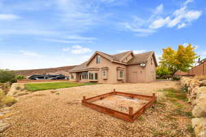 Rear view of house featuring stucco siding, a tile roof, and a vegetable garden