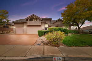 View of front of house featuring stucco siding, driveway, a tiled roof, and a front lawn