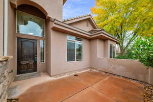View of exterior entry featuring stucco siding, a patio, and a tiled roof