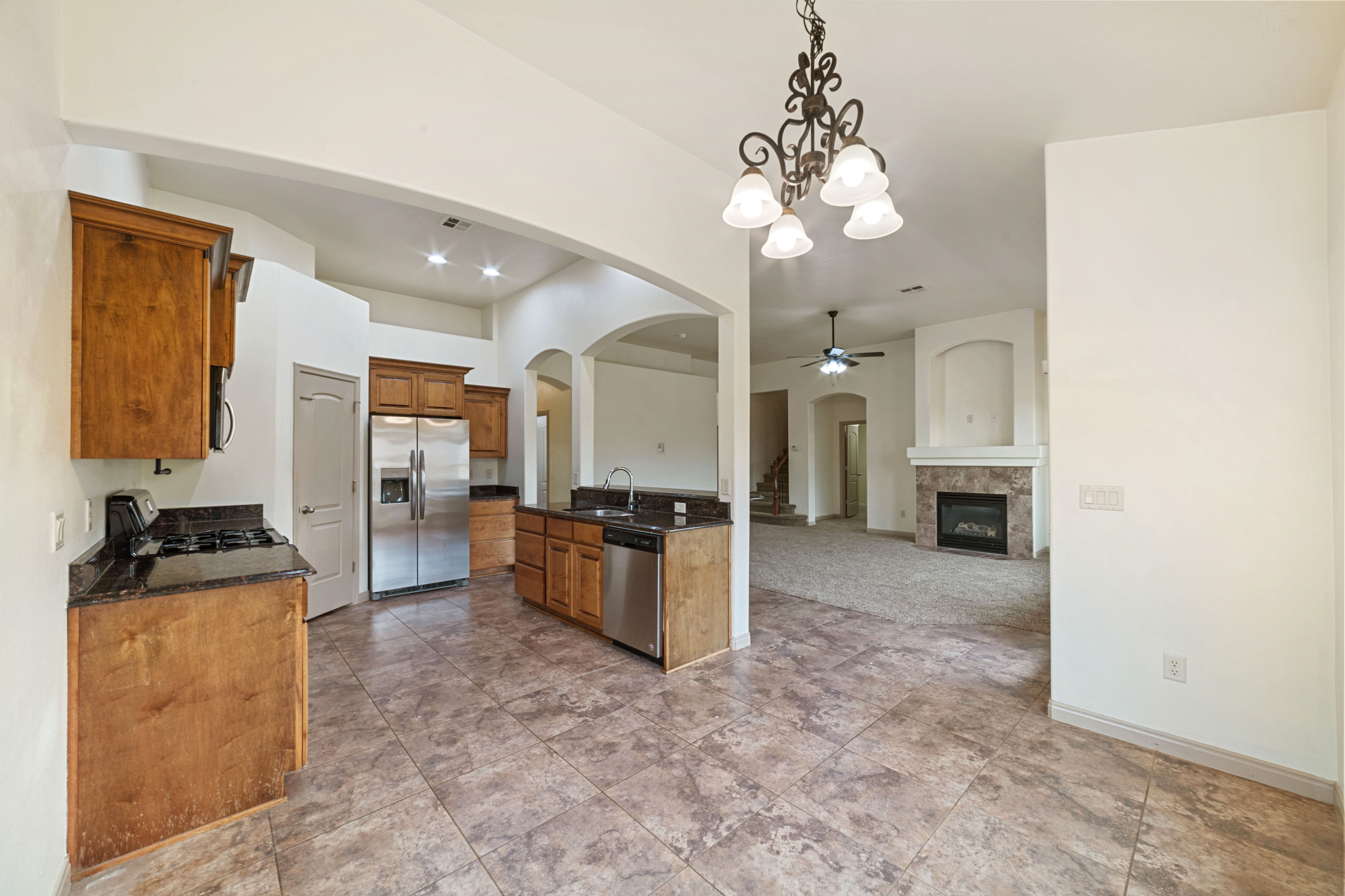 Kitchen with arched walkways, decorative light fixtures, a chandelier, appliances with stainless steel finishes, and open floor plan