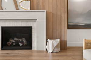 Detailed view of wood finished floors, a chandelier, wood walls, and a glass covered fireplace