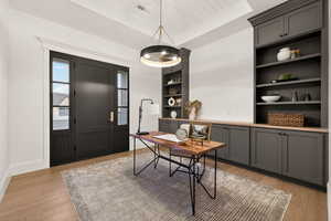 Home office with built in features, light wood-style floors, and wood ceiling