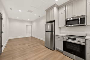 Kitchen featuring appliances with stainless steel finishes, light countertops, recessed lighting, light wood-type flooring, and gray cabinets