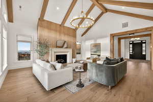 Living area with high vaulted ceiling, a fireplace, a chandelier, light wood-style floors, and beam ceiling