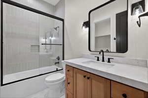 Bathroom with enclosed tub / shower combo, vanity, and marble finish floors