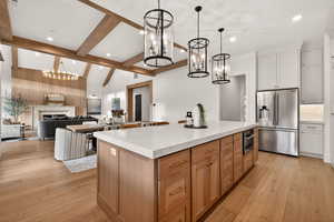 Kitchen featuring a chandelier, appliances with stainless steel finishes, a kitchen island, pendant lighting, and a fireplace
