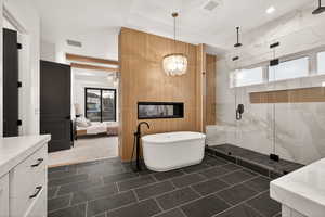 Ensuite bathroom with vanity, a marble finish shower, a soaking tub, and dark tile patterned floors