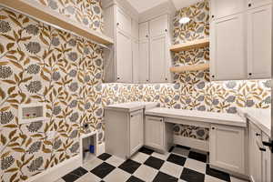 Laundry room with dark flooring, wallpapered walls, hookup for a washing machine, and cabinet space