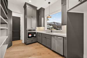 Kitchen featuring stainless steel appliances, gray cabinetry, decorative backsplash, and light wood-style floors