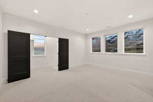 Unfurnished bedroom with light colored carpet and recessed lighting