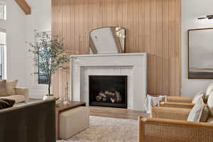 Living area with a brick fireplace, wood walls, wood finished floors, and a chandelier