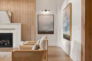Sitting room featuring wood finished floors, a brick fireplace, and wooden walls