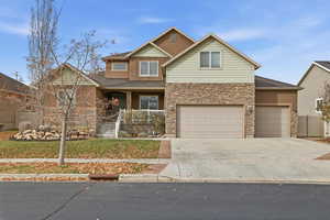 View of front of home with a porch, concrete driveway, stone siding, and stucco siding