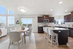 Kitchen featuring dark brown cabinets, a kitchen bar, a kitchen island, light wood-style flooring, and tasteful backsplash