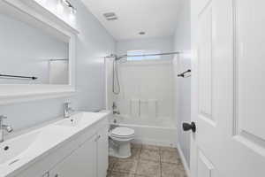 Bathroom with double vanity, washtub / shower combination, and light tile patterned floors