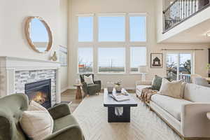 Living area with a towering ceiling, wood finished floors, and a fireplace