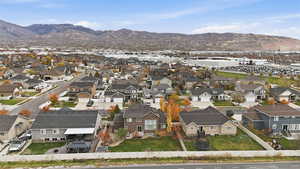 Aerial view of property and surrounding area featuring a mountain backdrop and nearby suburban area