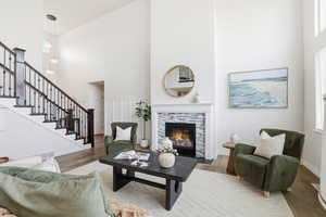 Living area with a high ceiling, stairs, a fireplace, and wood finished floors
