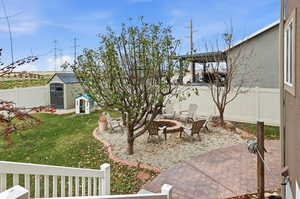 Fenced backyard with a fire pit, a patio, and a storage shed