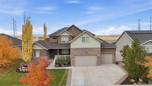 View of front of house with stone siding, covered porch, driveway, and a front lawn
