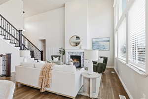 Living area with a tiled fireplace, a high ceiling, wood finished floors, and stairway