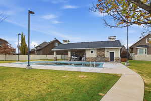 Rear view of house featuring a patio area, a fenced backyard, and stone siding