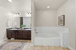 Bathroom with double vanity, a garden tub, recessed lighting, light tile patterned floors, and a textured ceiling