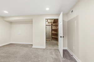 Unfurnished bedroom featuring ensuite bathroom, light carpet, and recessed lighting