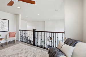 Living area featuring carpet, recessed lighting, a ceiling fan, and an upstairs landing