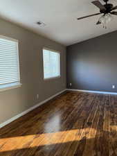 Empty room with dark wood-type flooring and a ceiling fan