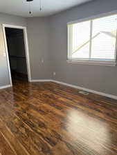 Empty room with dark wood-style floors and a ceiling fan