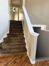 Staircase featuring wood finished floors and a ceiling fan
