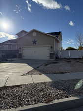 View of side of home with stone siding, concrete driveway, an attached garage, and stucco siding