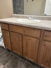 Bathroom featuring vanity, dark tile patterned floors, and a shower