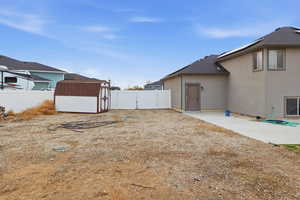 Fenced backyard with a storage unit and a patio area