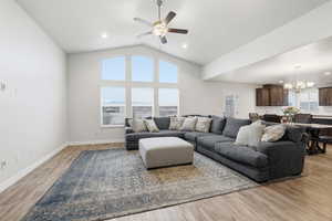 Living room featuring a chandelier, ceiling fan, light wood finished floors, and high vaulted ceiling