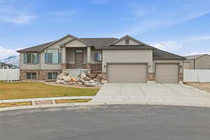 View of front of property featuring stucco siding, driveway, an attached garage, brick siding, and a porch
