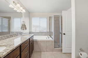 Full bath with double vanity, a bath, light tile patterned floors, and a shower stall