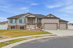 View of front facade with stucco siding, driveway, an attached garage, and brick siding