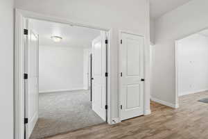 Hall featuring light wood-style flooring and light carpet