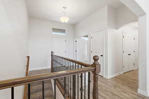 Hallway with light wood-type flooring, arched walkways, and an upstairs landing