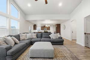 Living room with ceiling fan, light wood finished floors, a chandelier, recessed lighting, and a towering ceiling