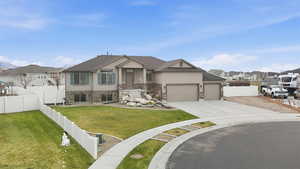 View of front facade featuring a fenced backyard, a residential view, stucco siding, driveway, and a garage