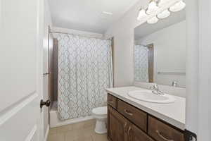 Bathroom with vanity, light tile patterned floors, and shower / bath combo with shower curtain