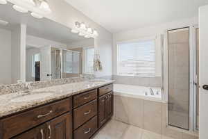 Bathroom with double vanity, a stall shower, a garden tub, and light tile patterned flooring