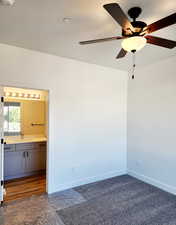Empty room with ceiling fan, a textured ceiling, and dark colored carpet