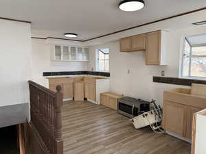 Kitchen featuring light brown cabinetry, stainless steel microwave, dark wood finished floors, glass insert cabinets, and a textured ceiling