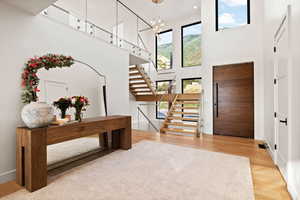 Entrance foyer featuring light wood-type flooring, a chandelier, stairs, and a high ceiling