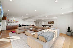 Living room featuring wet bar, light wood-style floors, and recessed lighting