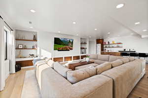Living room featuring built in shelves, light wood-style floors, and recessed lighting